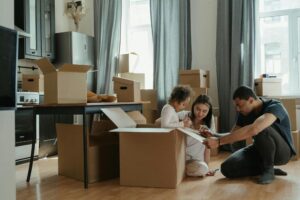 Couple sitting in between moving boxes on the floor.